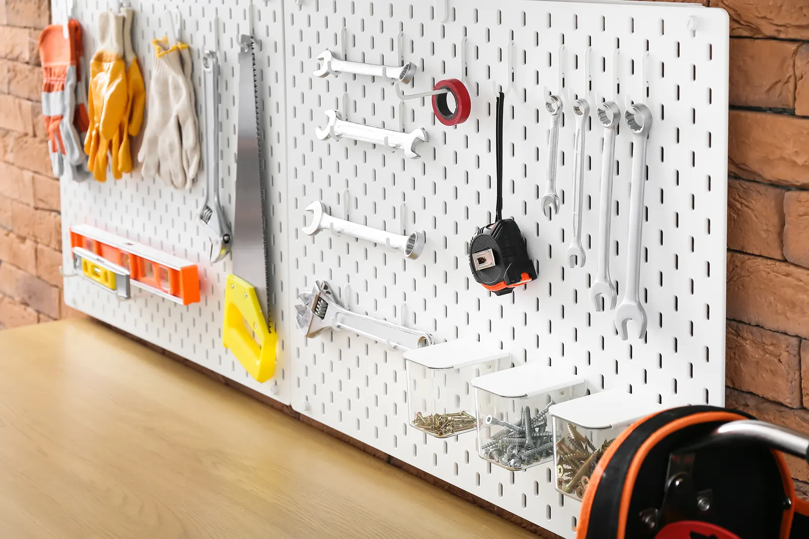 Hand tools and wrenches hung neatly on a white pegboard above a garage workbench